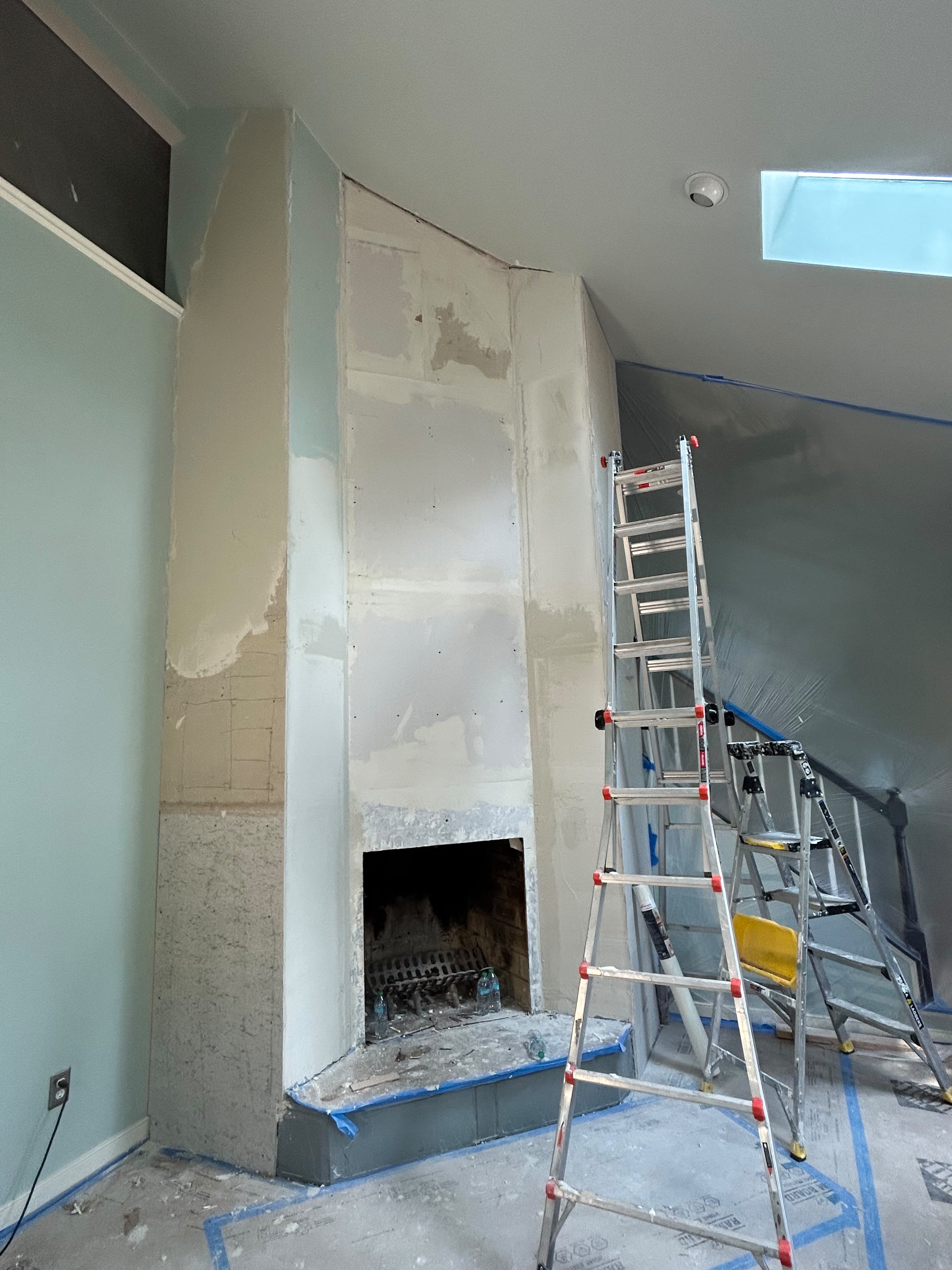 Corner fireplace mid-renovation — room painted, lower tile section in progress