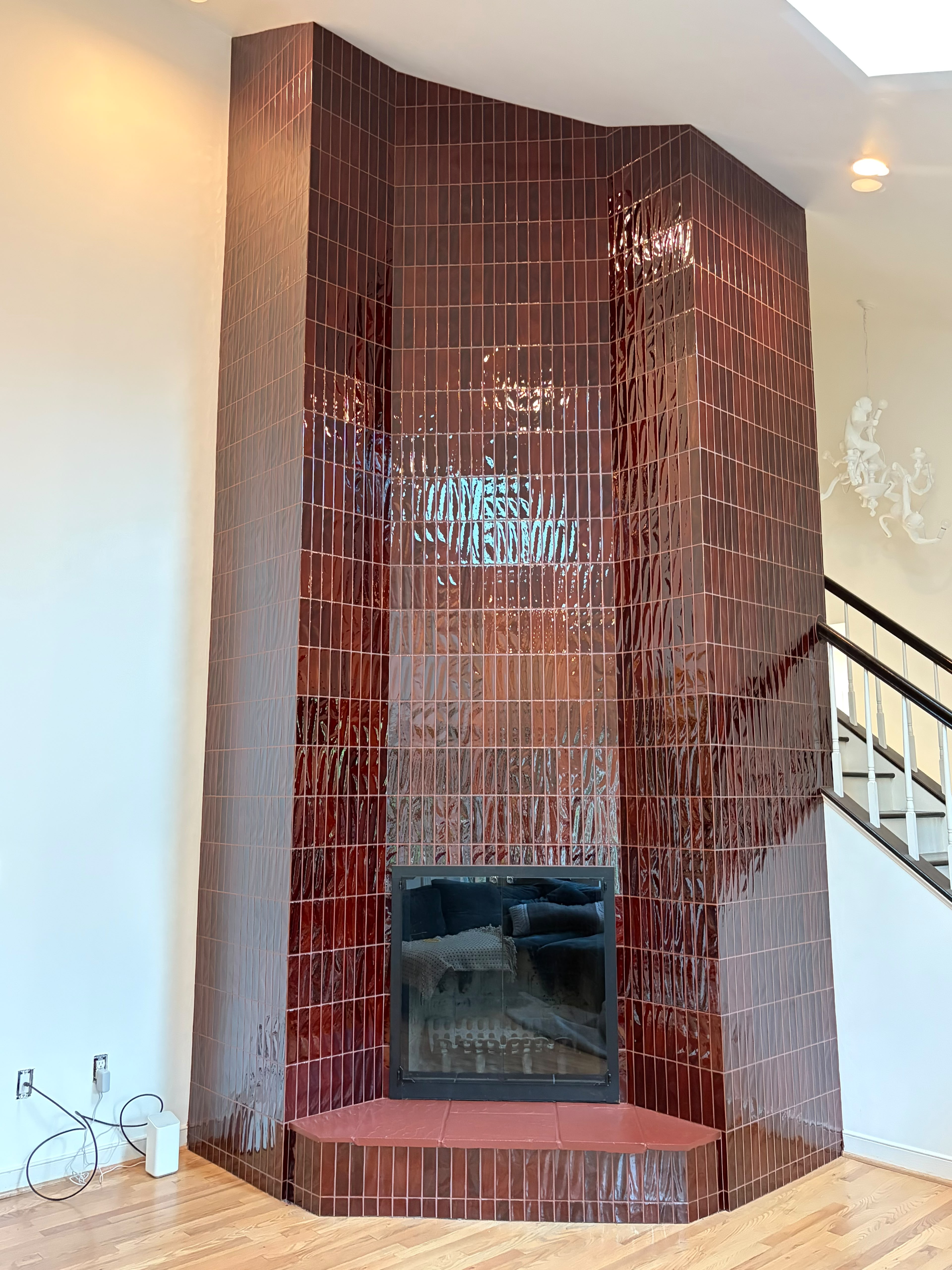 Finished corner fireplace — dramatic floor-to-ceiling deep red glossy tile surround